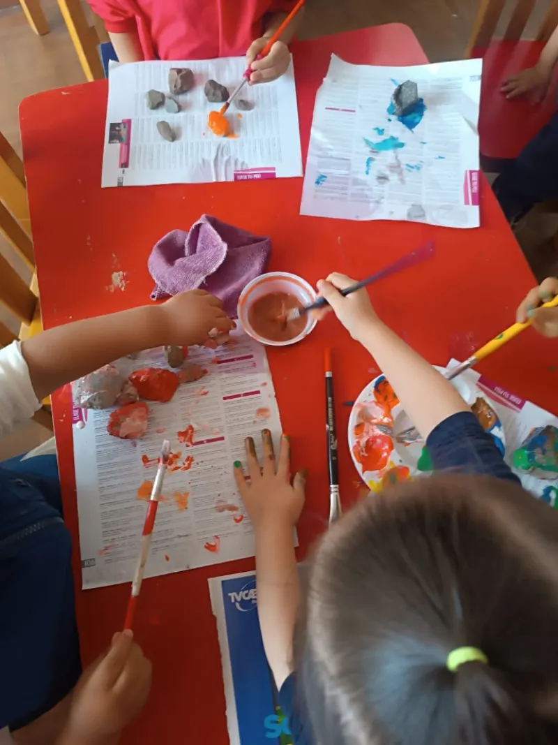Niños pintando piedras con témperas en taller de arte del centro infantil Años Mágicos