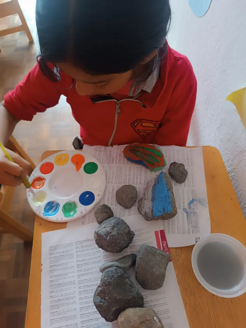 Niña pintando piedras con paleta de colores en actividad creativa guardería Quito